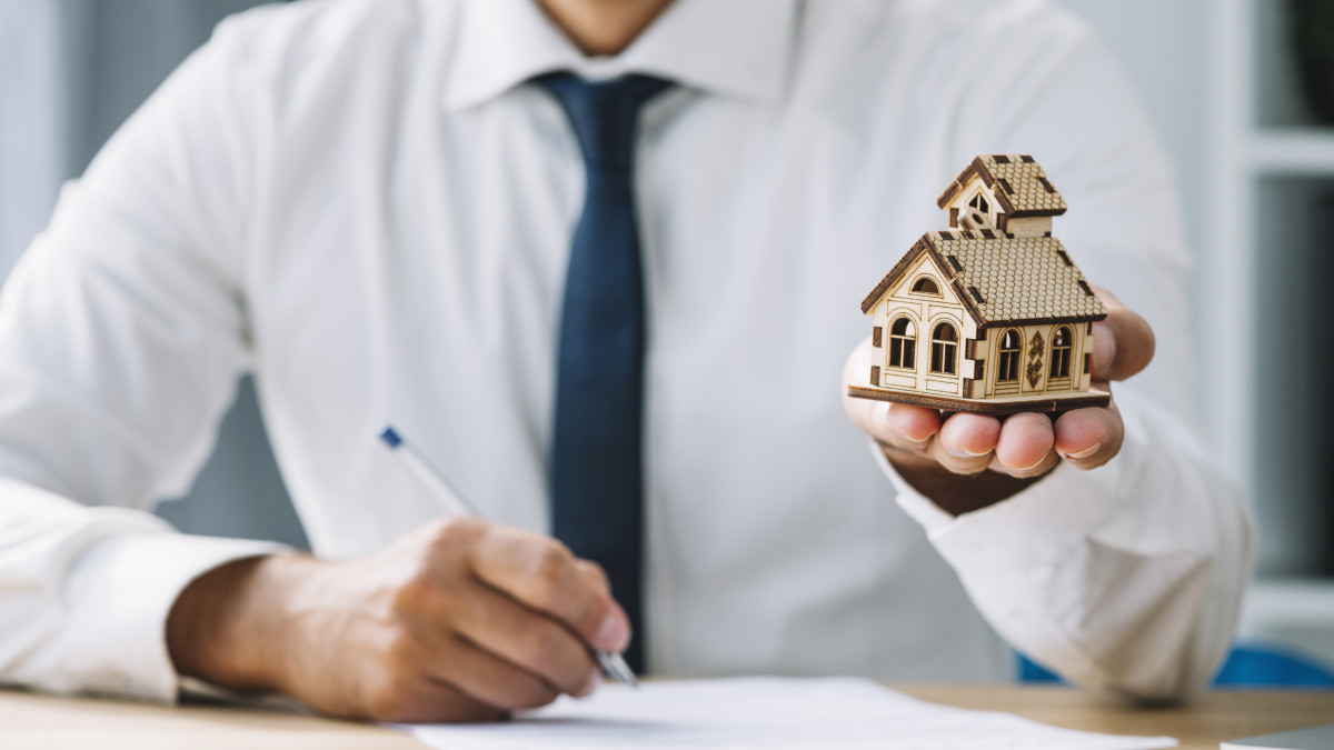 un homme est expert immobilier et présente une maisonnette en bois