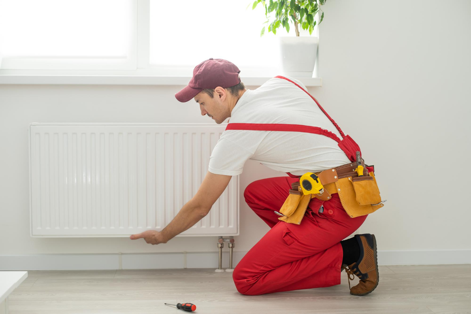 Jeune plombier installant un système de chauffage dans un appartement