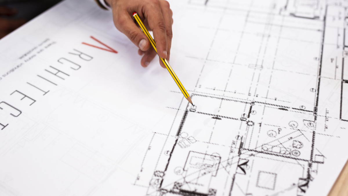 Main d'un professionnel de la construction est en train d'élaborer un plan.